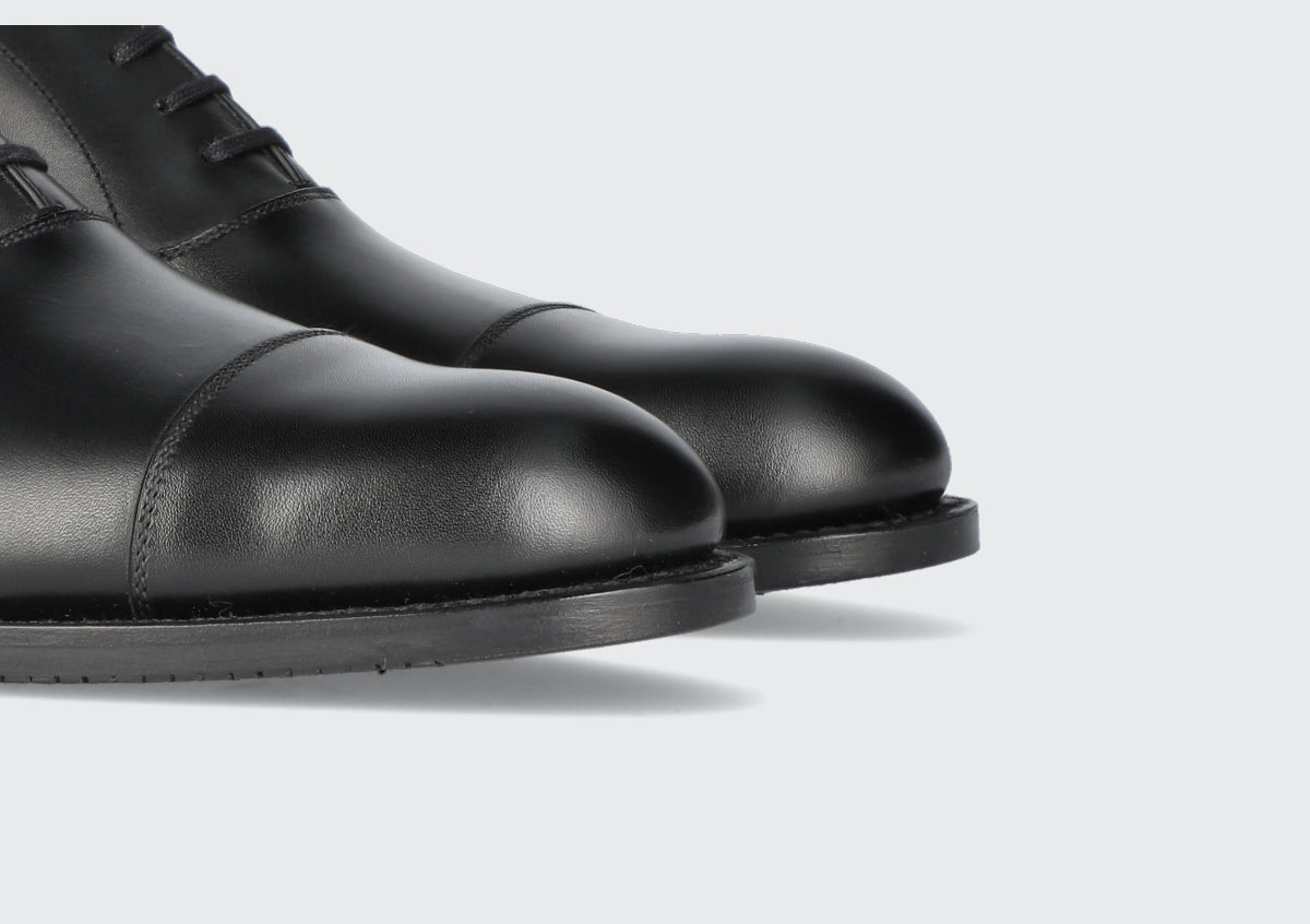 The toes of a pair of black men's dress shoes from the Hartt Shoe Company
