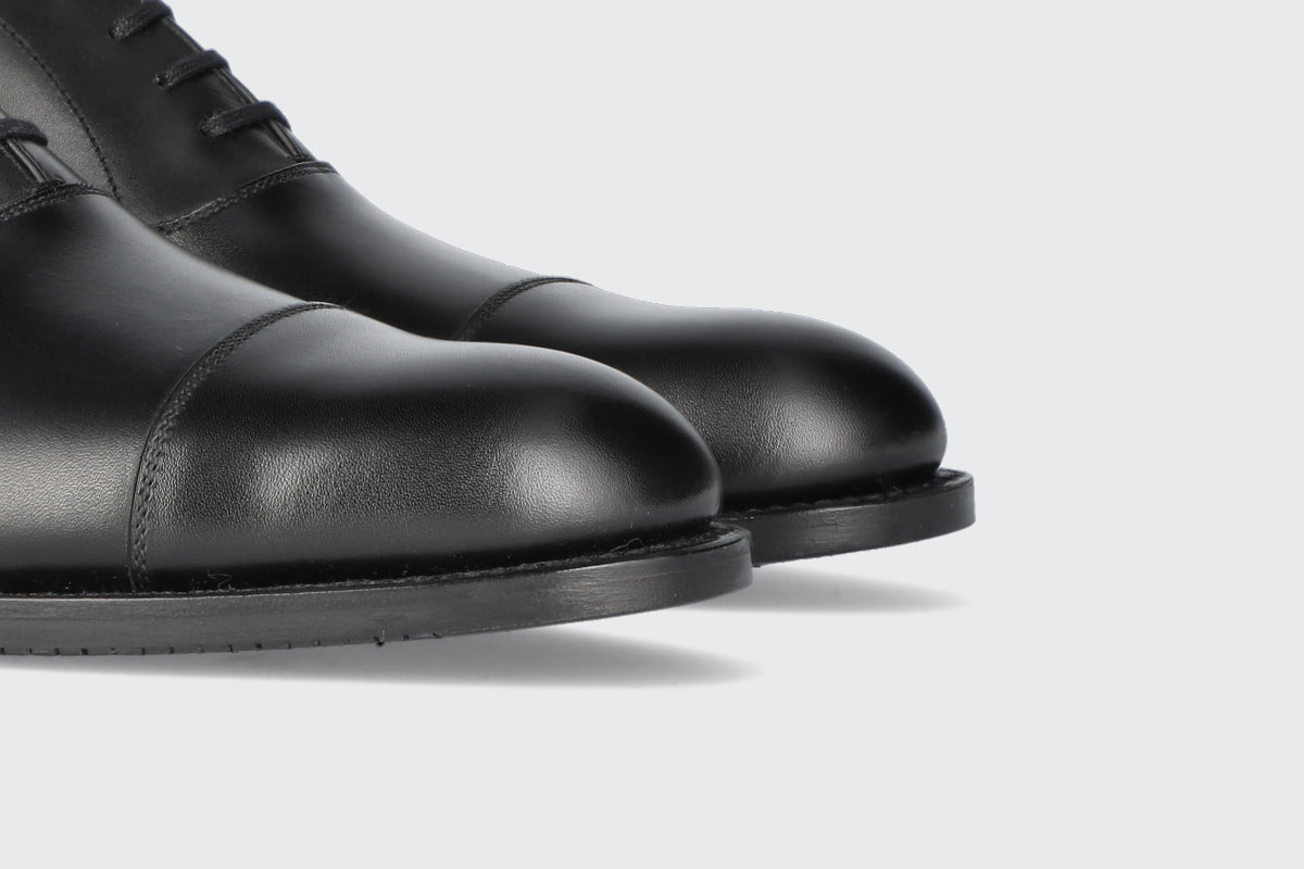 The toes of a pair of black men's dress shoes from the Hartt Shoe Company