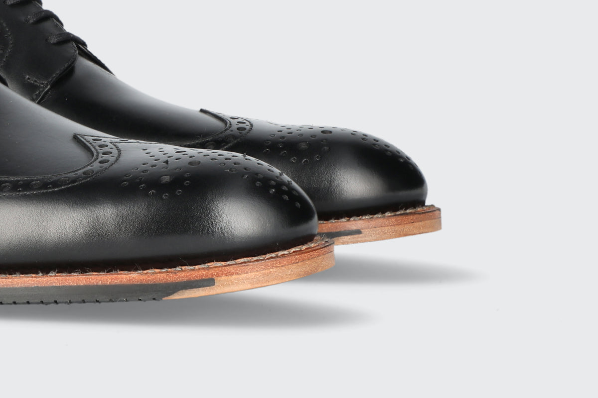 The toes of a pair of black leather dress shoes from the Hartt Shoe Company