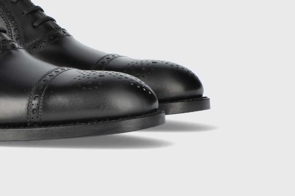 The brogued toes of a pair of black leather shoes from the Hartt Shoe company