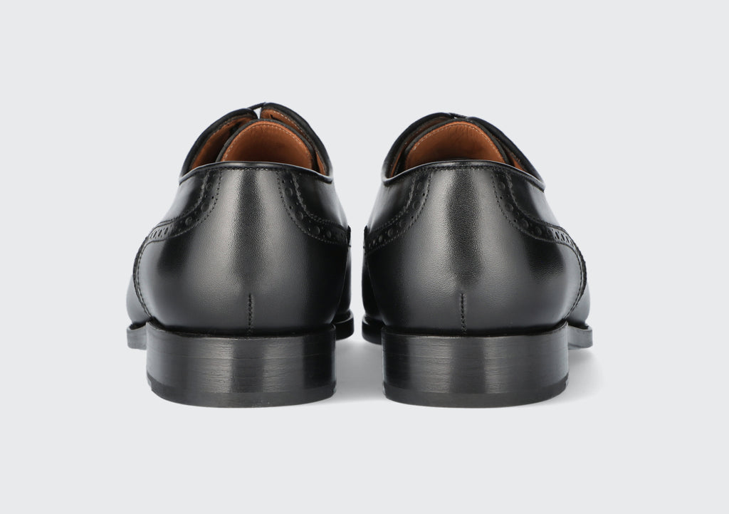 The heels of pair of black leather dress shoes from the Hartt Shoe Company