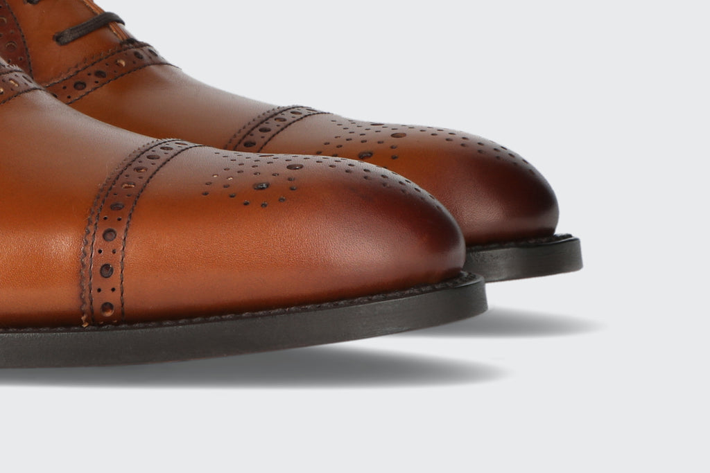 The toes of a pair of brown leather dress shoes with brogueing from the Hartt Shoe Company